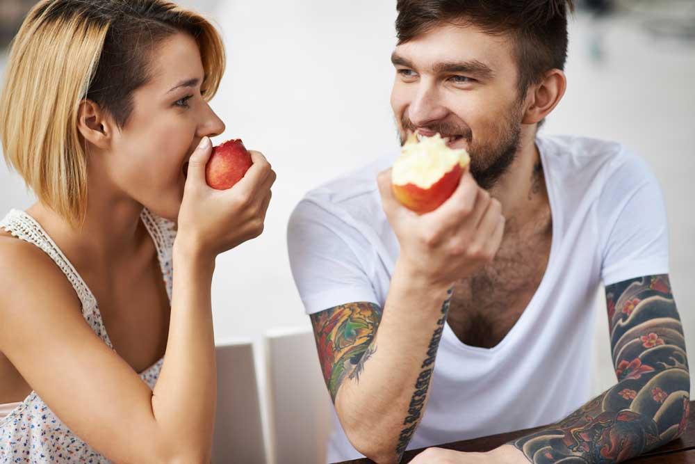 Man and woman eating apples and looking at each other