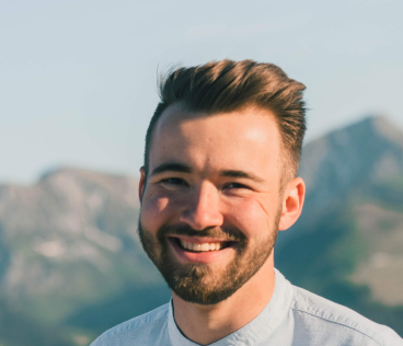 Man smiling in front of mountain range